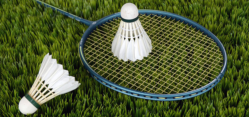 Badmintonracket ligger på marken och ovanpå ligger en badmintonboll.