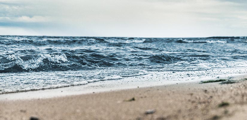 Vy över havet, man ser havet med vågor och lite av sandstranden.